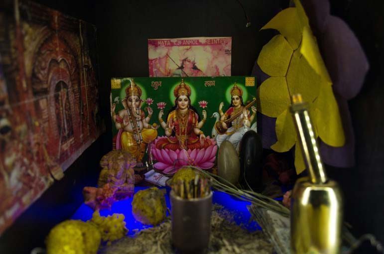 In a Nepali construction worker’s bedroom, a cardboard box hold depictions of Hindu deities.